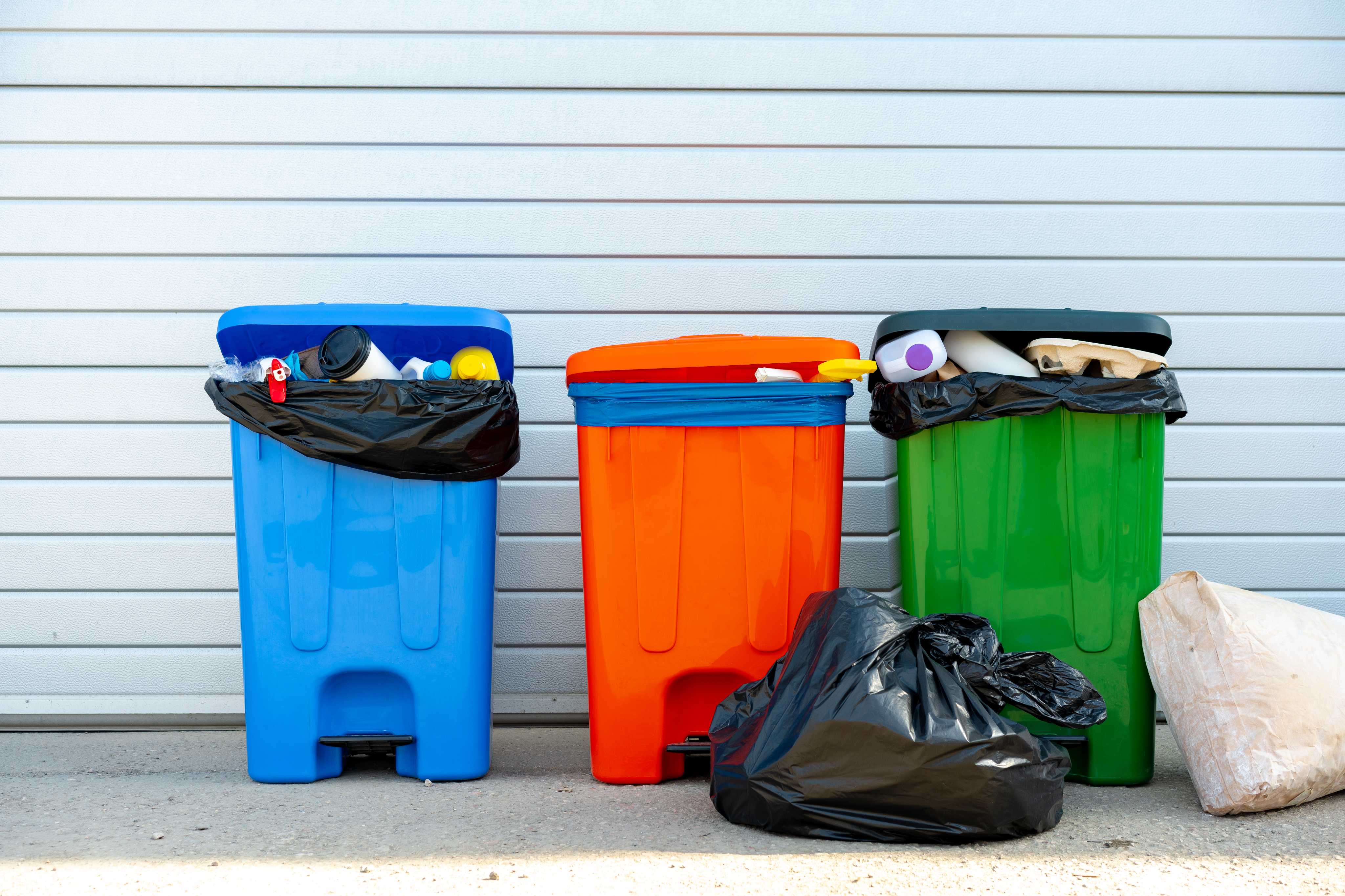 three-trash-containers-full-of-garbage-near-the-dumpster